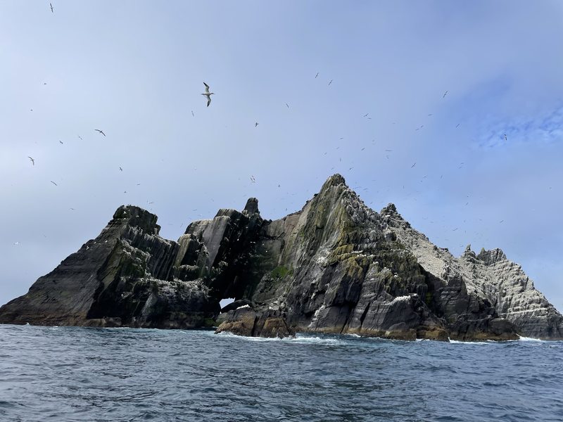 A steep, rocky island rises from the Atlantic beneath circling seabirds in the Skellig Islands.